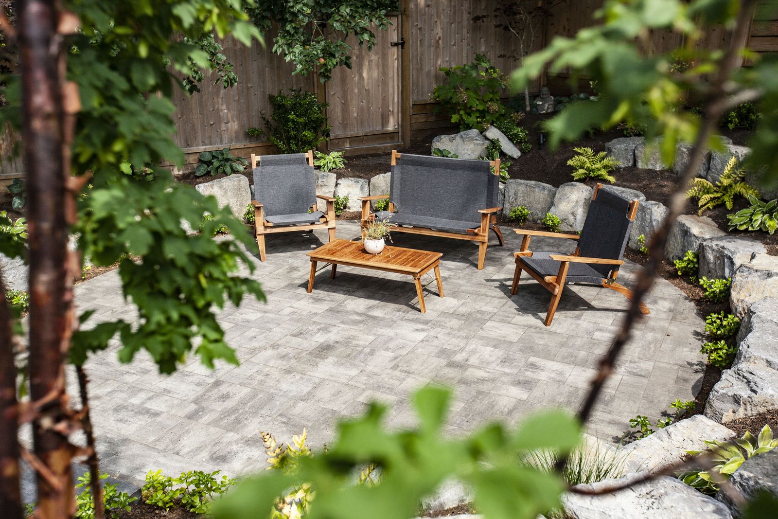 Round paver patio with lounge chairs and boulders